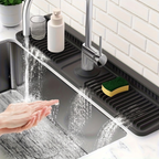 Kitchen sink with a black over-the-sink dish drying rack, hand washing hands, and cleaning supplies.