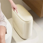 Beige trash can with a hand reaching to open it on a neutral background