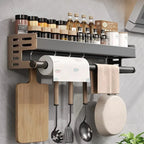 Wall-mounted kitchen organizer with cutting board, utensils, and paper towel holder.