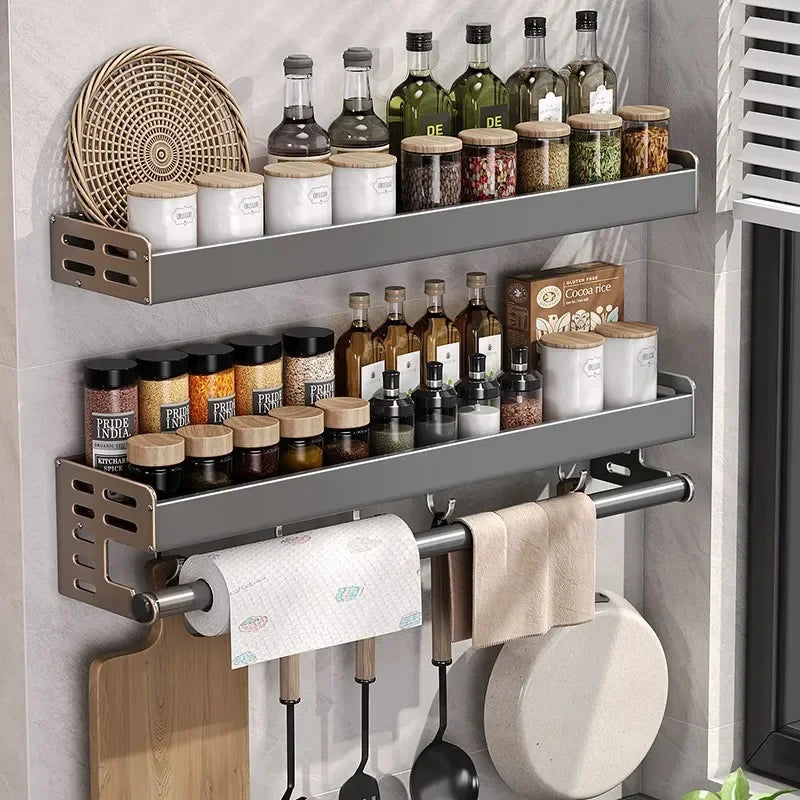 Kitchen shelf with spices, bottles, and a paper towel holder on a wall.