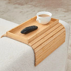 Wooden tray on a bed with a cup of coffee and remote control