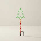 A Christmas tree-shaped outdoor light with a red and white striped pole and a black ground stake, shown against a plain light gray background.