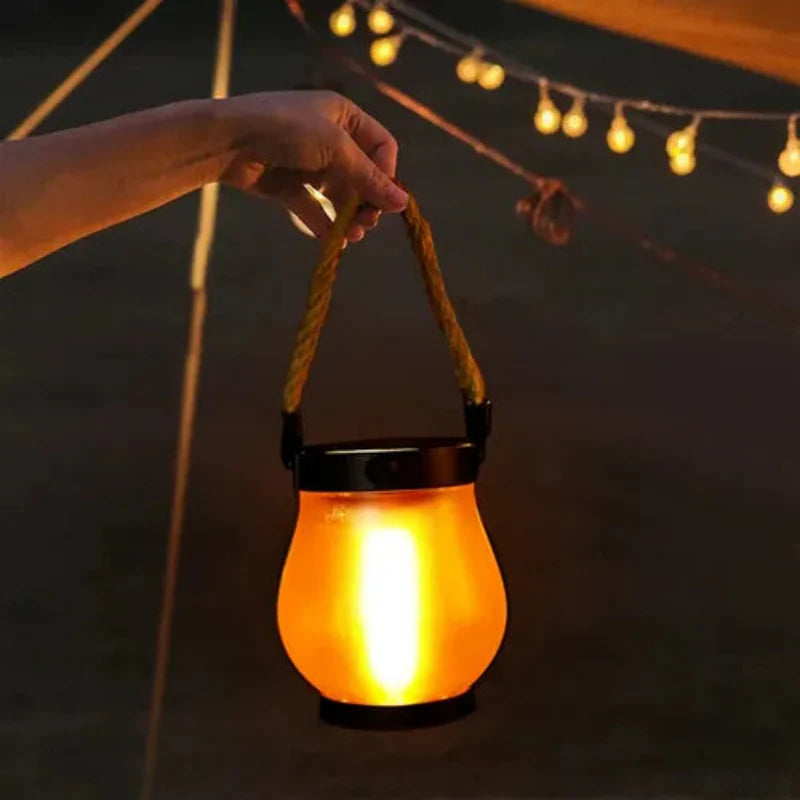 Hand holding a glowing lantern under string lights at night