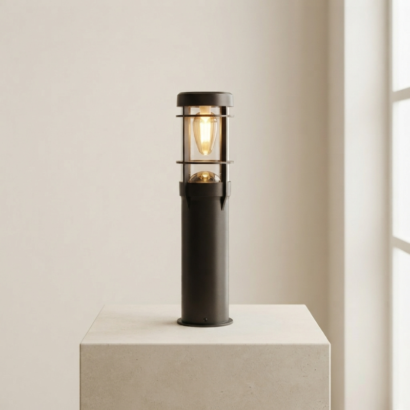 Black outdoor lamp on a white pedestal against a beige wall