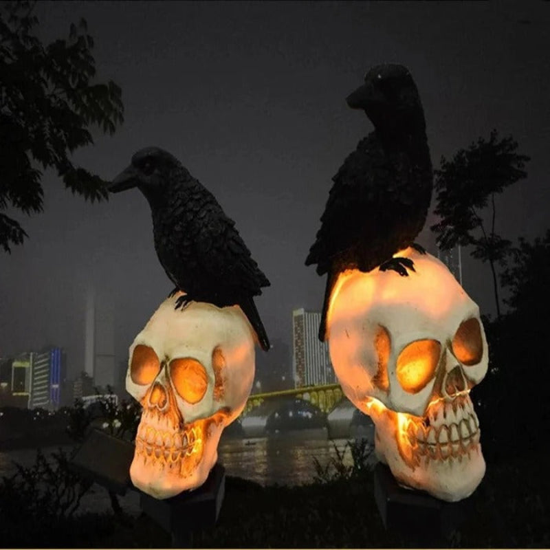 Two illuminated skull lamps with crows on top against a dark cityscape background
