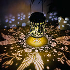 Decorative lantern casting bird and floral shadows on a dark surface