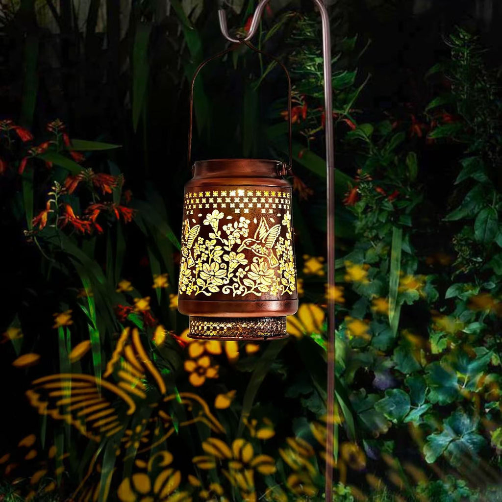Decorative lantern with floral patterns casting shadows on a garden at night