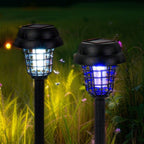 Two solar-powered outdoor lights with bug zappers in a grassy area.