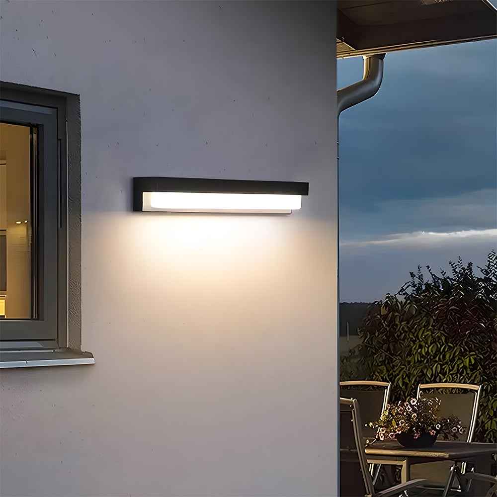 Modern outdoor wall light fixture on a house exterior with a view of a patio area.