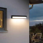 Modern outdoor wall light fixture on a house exterior with a view of a patio area.