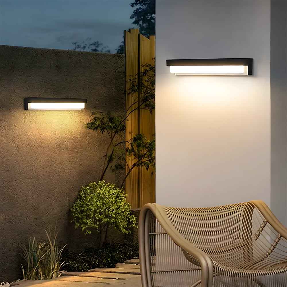 Outdoor wall lights illuminating a garden area with a wicker bench.