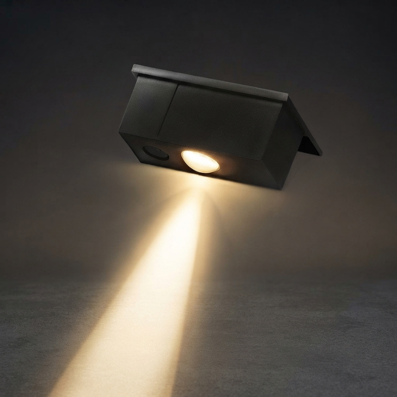 Black outdoor wall light fixture emitting a beam of light on a dark background