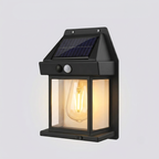 Solar-powered outdoor wall light with a clear glass cover on a gray background