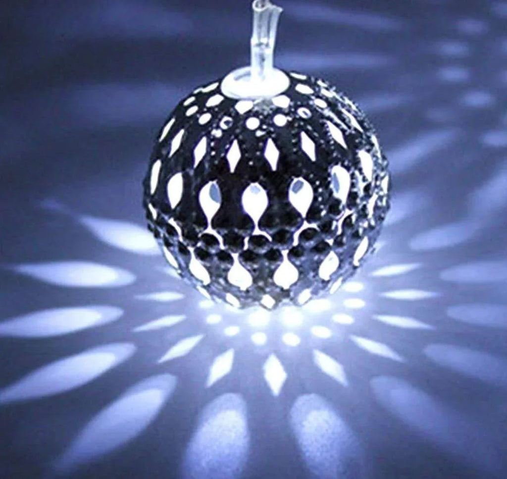 Decorative glass ball with cut-out patterns on a dark background