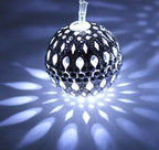 Decorative glass ball with cut-out patterns on a dark background