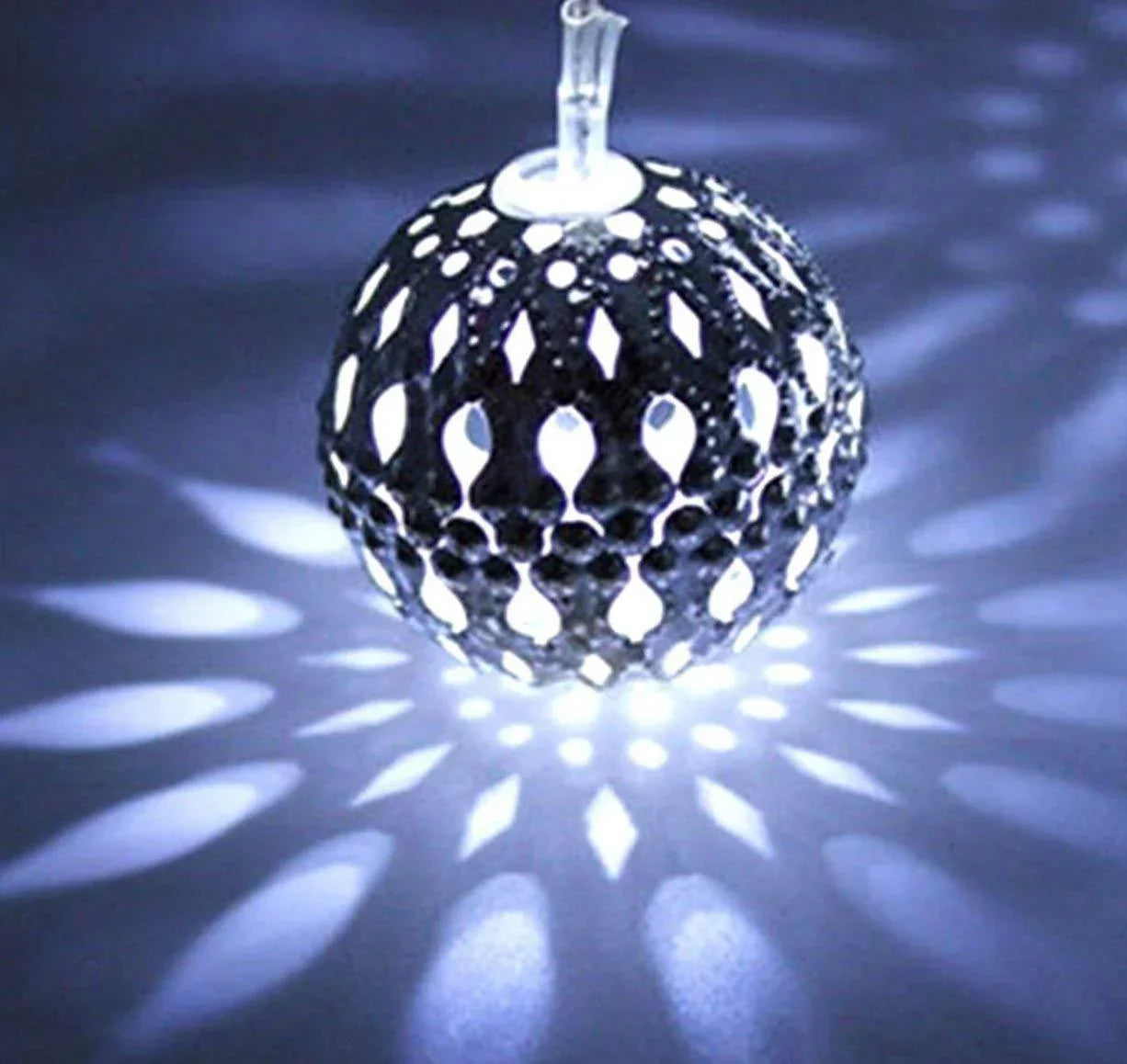 Decorative glass ball with cut-out patterns on a dark background