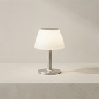 Small table lamp with a white shade and metallic base on a neutral background