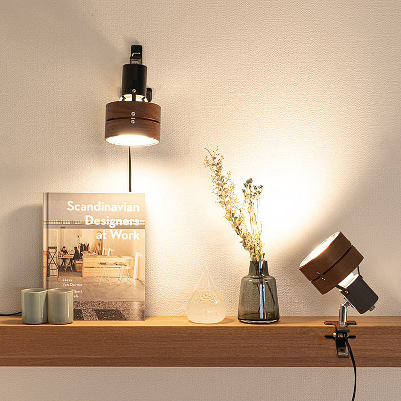 Wooden shelf with decorative items including a book, vase with flowers, and lamp on a neutral wall background
