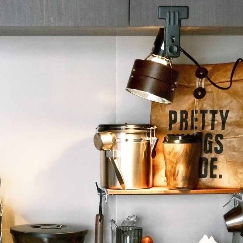 Decorative shelf with metallic containers and a lamp, featuring a motivational sign in the background.