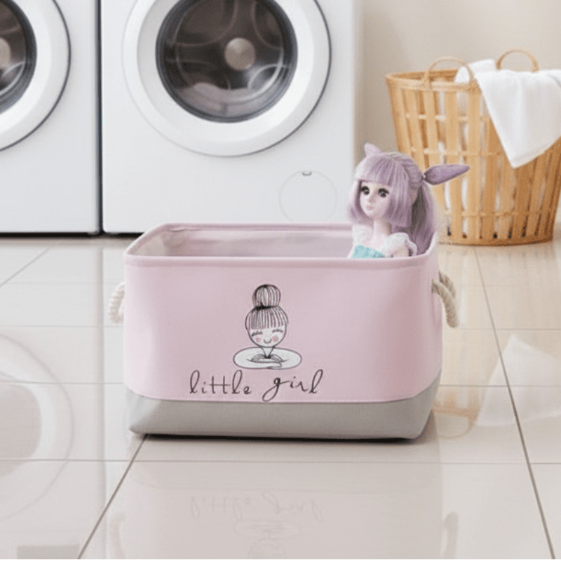 Pink storage basket with a cartoon design labeled 'little girl' in a laundry room.