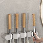Set of four metal hooks with wooden handles on a gray wall.