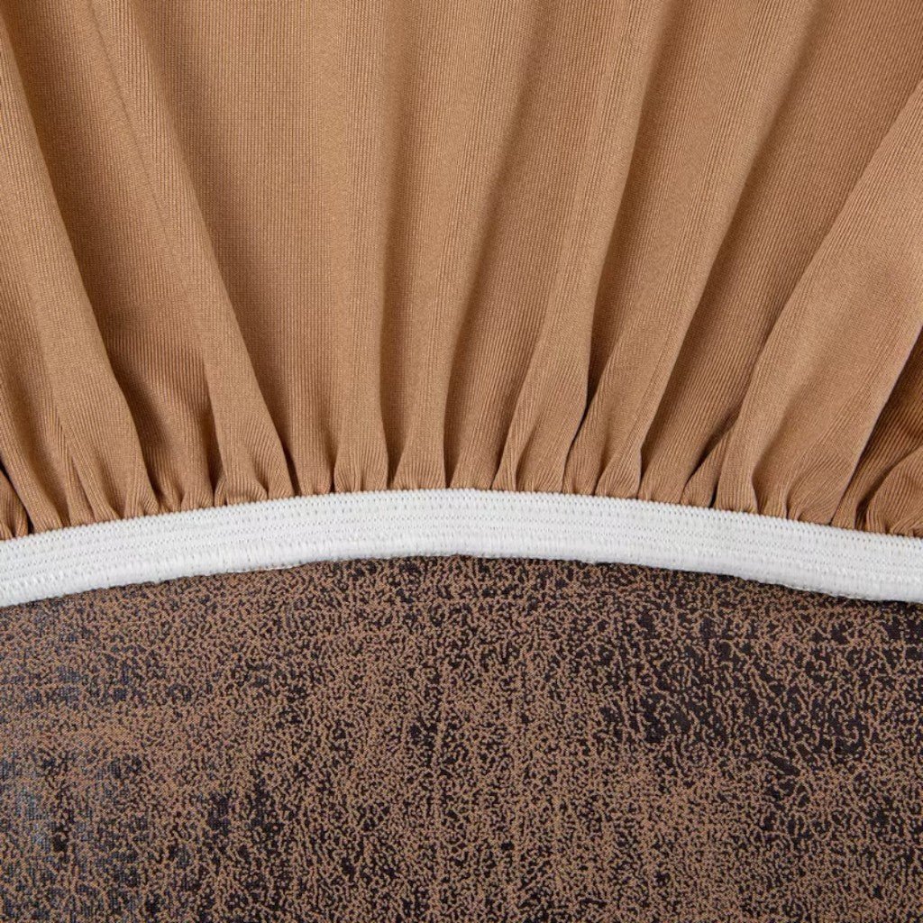 Close-up of a brown fitted sheet with a white elastic band on a bed.