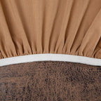 Close-up of a brown fitted sheet with a white elastic band on a bed.