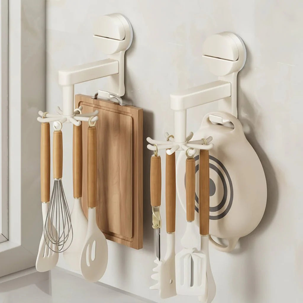 White wall-mounted kitchen utensil organizer with wooden-handled tools hanging on a light wall beside a window.