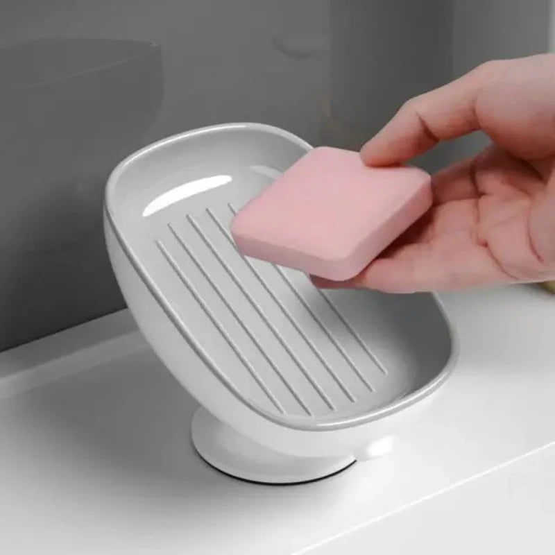 Person placing a pink soap bar into a white soap dish on a bathroom counter.