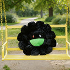 Black plush flower with a green center on a yellow swing set in a park.