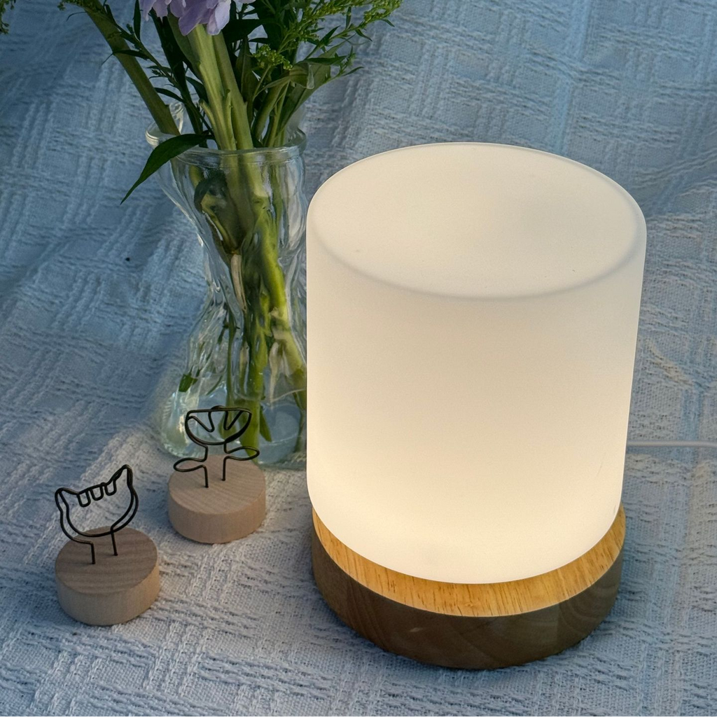 Fragrant oil diffuser emitting a soft glow on a textured blue surface with flowers and decorative items.