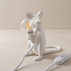White mouse-shaped lamp with a visible bulb on a beige surface
