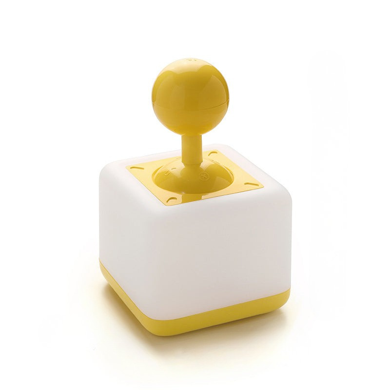 A retro-style toy joystick with a white cube base, yellow bottom trim, and a yellow spherical knob, photographed on a clean white background.
