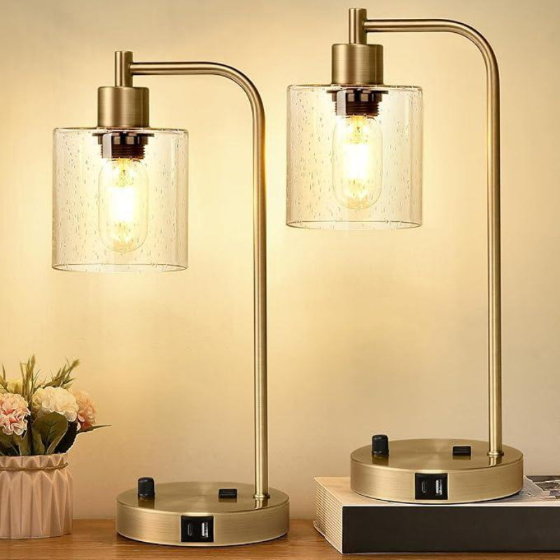 Pair of gold table lamps with glass shades on a wooden surface.