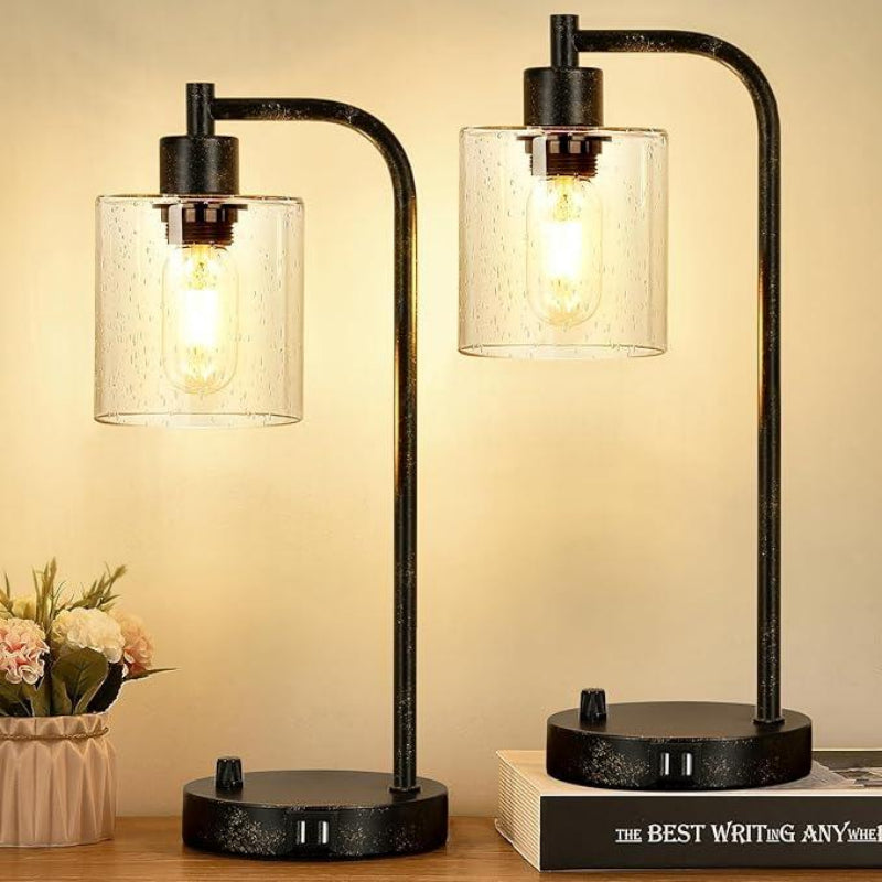 Two black table lamps with glass shades on a wooden surface.