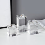 Set of three clear glass candle holders with candles on a light surface.