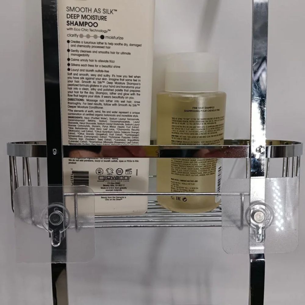 Shampoo bottle and bottle of conditioner on a clear shower caddy with a white background