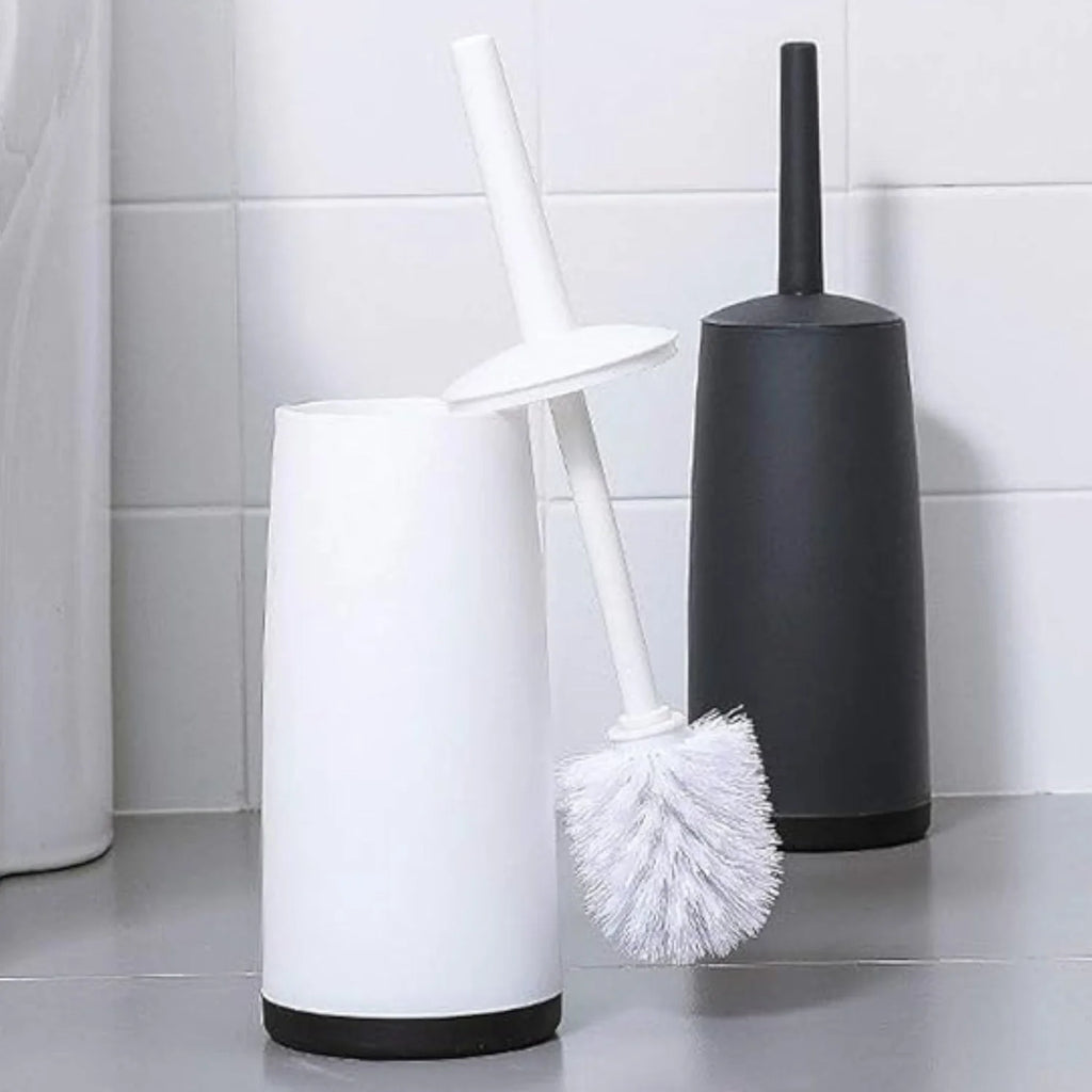 Two toilet brushes, one white and one black, against a tiled bathroom wall.
