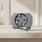 Gray metal object with circular design and metallic components on a beige surface