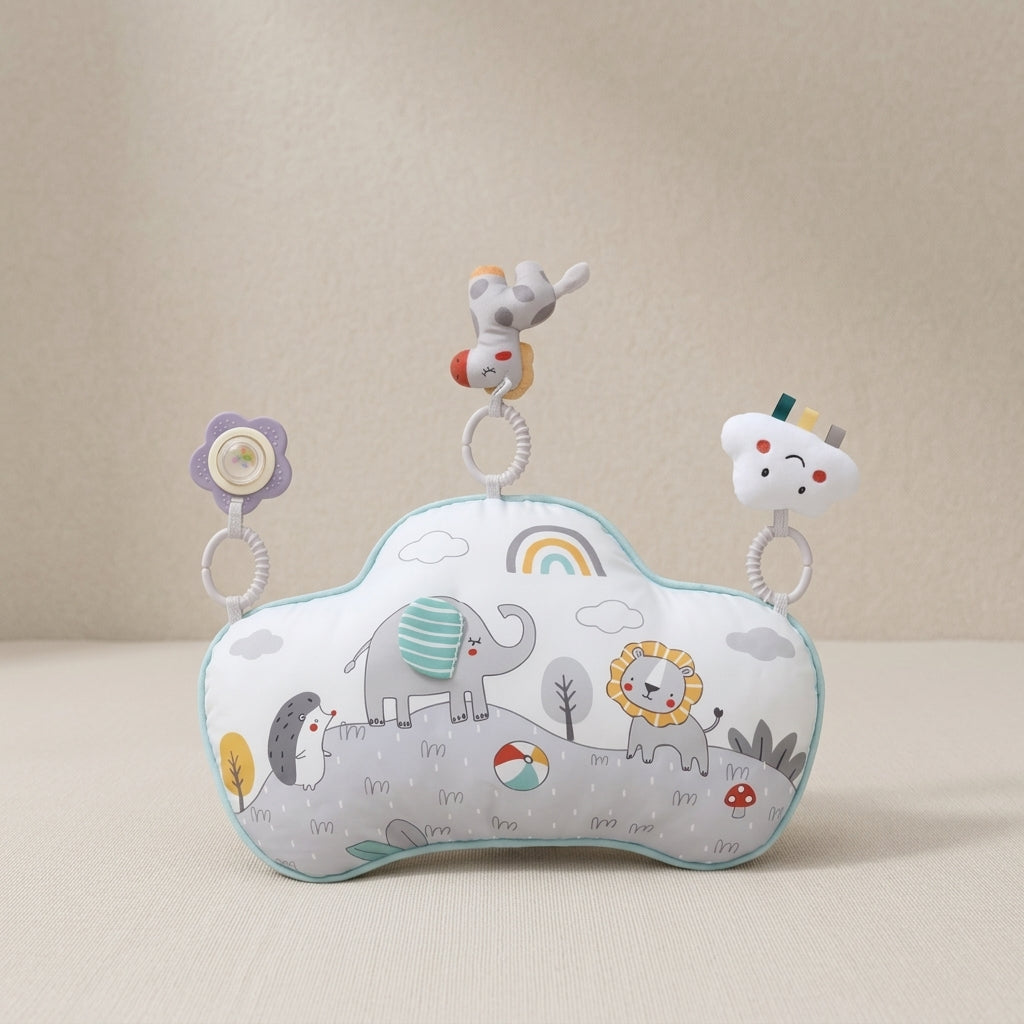 A baby sensory pillow with a cloud-shaped design, featuring a printed safari animal pattern with an elephant, lion, penguin, and rainbow. It has three hanging sensory toys: a flower, a monkey, and a smiling cloud.