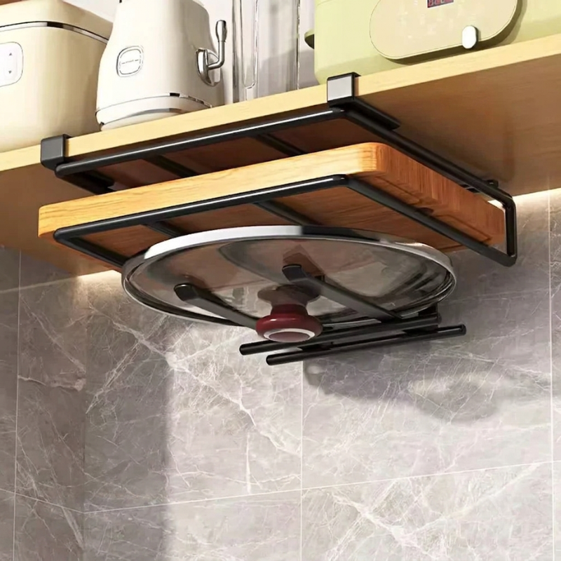 A black metal under-shelf kitchen organizer holding a wooden board and a glass lid, mounted beneath a light wood shelf in a kitchen setting with gray marble tile backsplash.