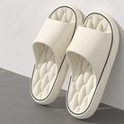 Pair of white slippers with quilted sole on a gray surface