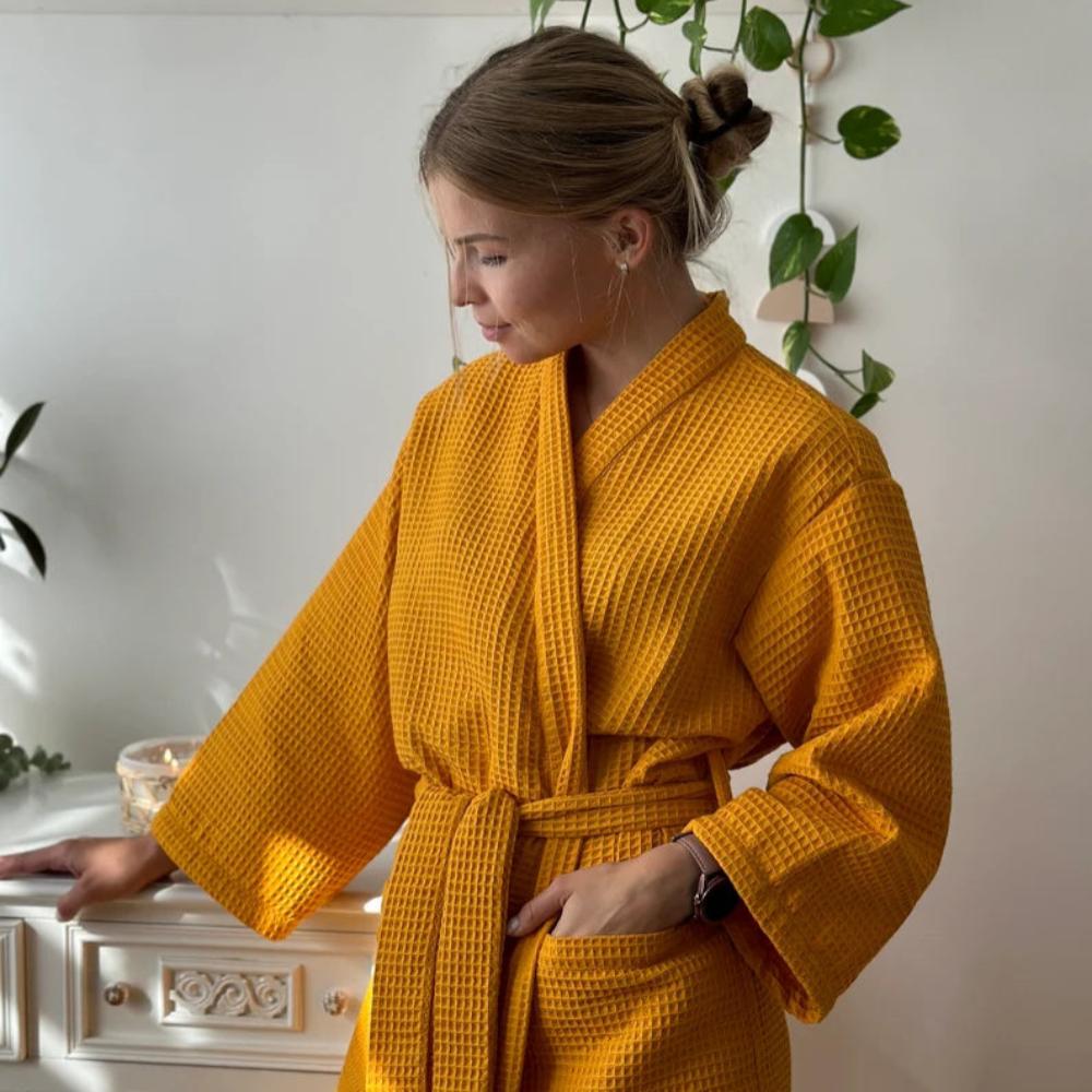Woman wearing a yellow robe in a room with plants