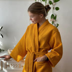 Woman wearing a yellow robe in a room with plants