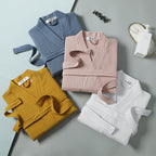 Four folded robes in blue, pink, yellow, and white on a gray surface.