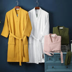 Yellow, white, and pink robes hanging on a dark blue wall with a green vest and basket.