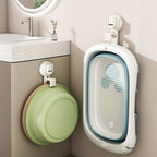 Collapsible bathtub and green basin hanging on a wall in a bathroom setting.