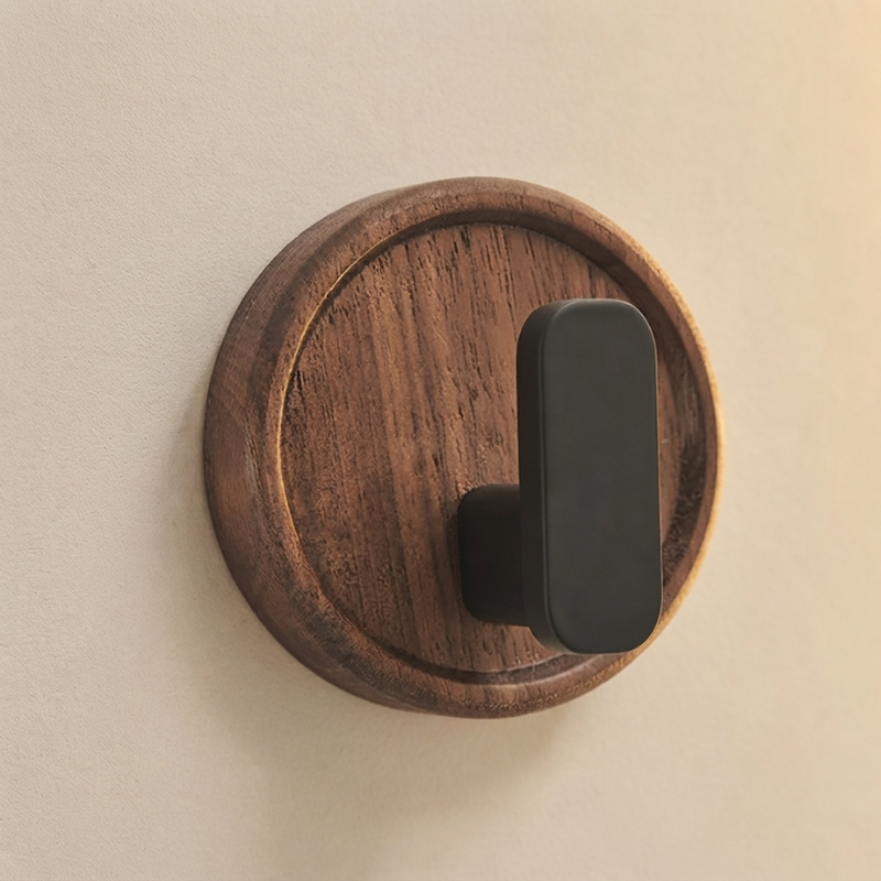 Wooden wall hook with a black metal hook on a beige background