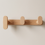 Wooden wall hook with three hooks on a beige background