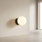Modern wall-mounted light fixture on a neutral wall with a window in the background